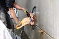 Arbeiter schneidet mit hydraulischer Ringsge eine Betonwand